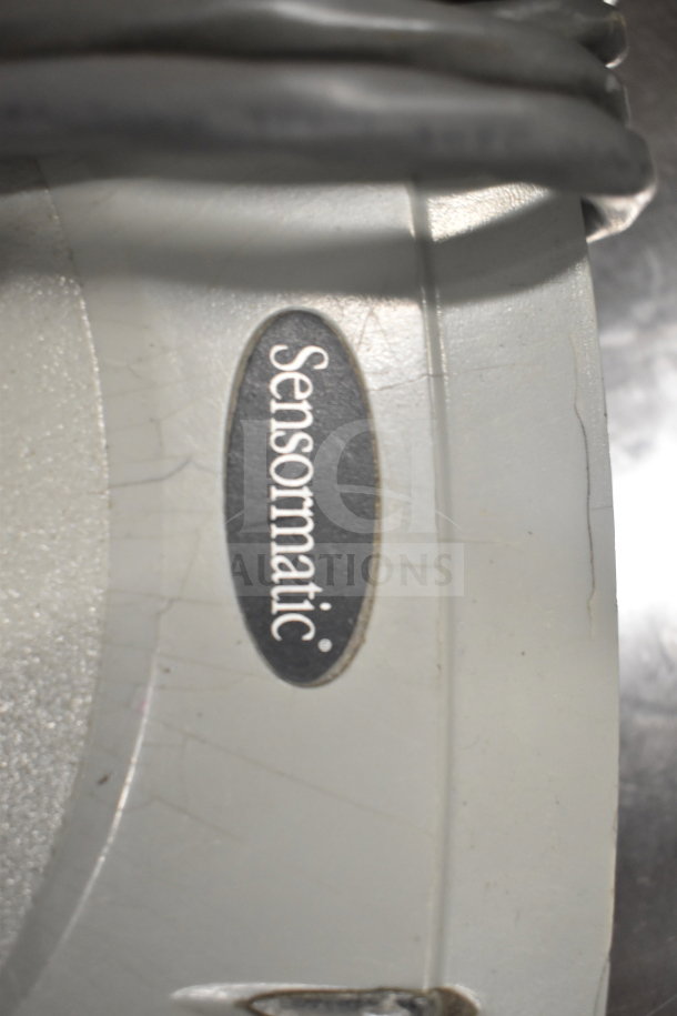 Close-up of Sensormatic device label, part of an auction lot including Dell computer towers and office telephones.