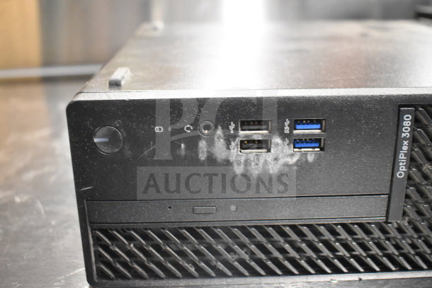 Dell OptiPlex 3080 computer tower showing front ports, lightly used, includes USB and audio jacks, visible minor wear.
