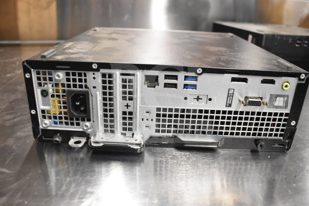 Rear view of a Dell computer tower showing power supply, USB ports, and ventilation grilles. Dusty surface, auction item.