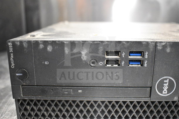Dell OptiPlex 3050 computer tower, showing USB ports and Dell logo. Dusty condition. Part of 12-item auction lot.