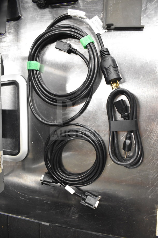 A bundle of various cables, including power and VGA cords, neatly coiled on a table.