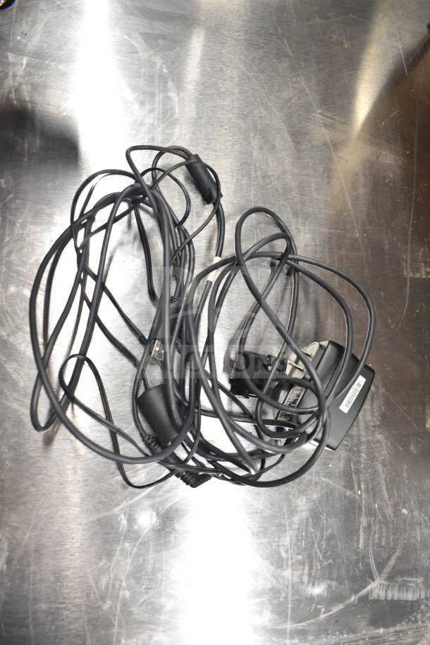 Tangled black cords and adapter on a metallic surface, part of an auction lot with Dell computer towers and more.