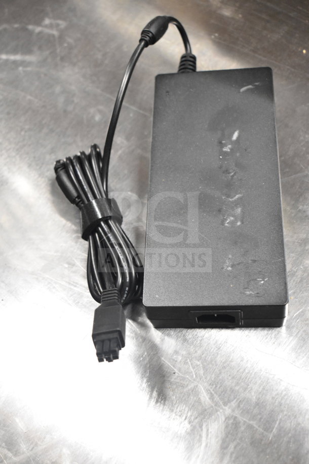 Black Dell power adapter with attached cord and Velcro strap, shown on a reflective surface.