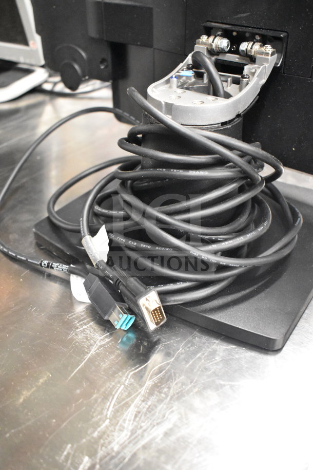 A coiled power cable with USB and VGA connectors next to a Dell computer tower on a metal surface.