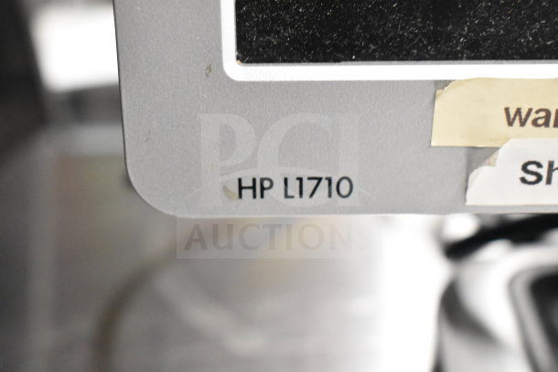 Close-up of HP monitor model L1710 label, part of auction lot including Dell computer towers, office phones, credit card reader.