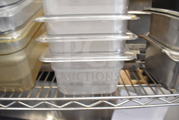 Two-tiered lot of clear and metallic drop-in bins on a metal shelf, showing used condition, no visible labels.