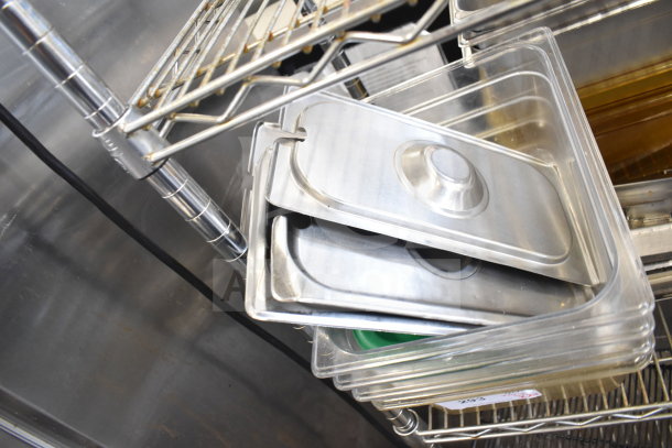 Two-tiered lot featuring various items, including metal lids and clear plastic drop-in bins on metal shelving.