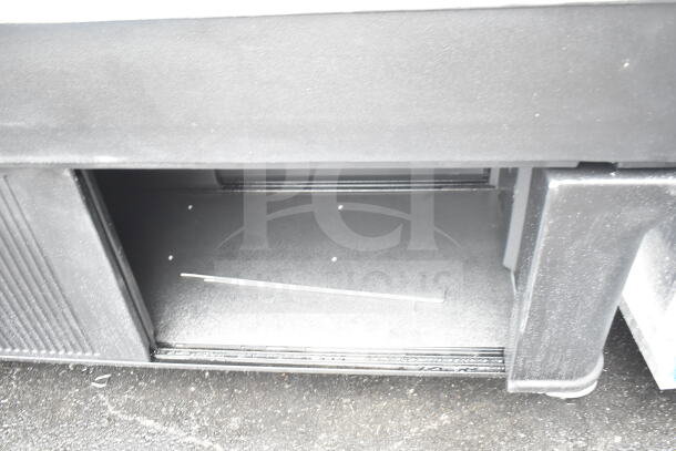 Black portable buffet station with minor scratches and dents, open storage compartment, and durable construction.