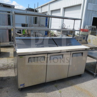 Turbo Air MST-72N refrigerated prep table with cutting board, three doors, two racks, two stainless steel shelves, on casters.