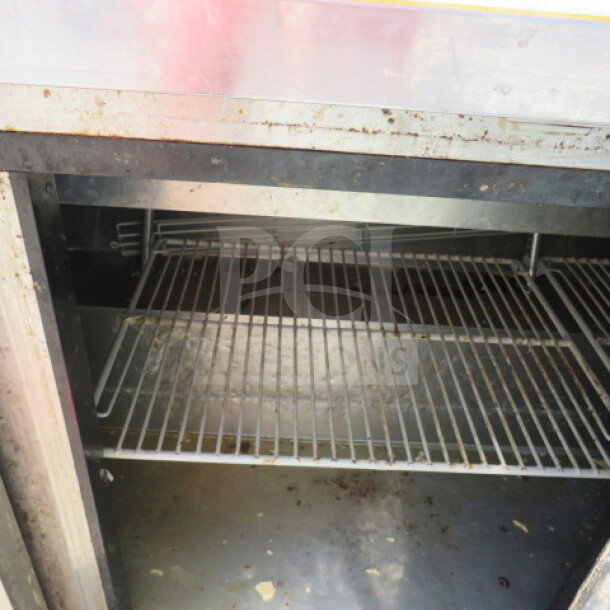 Turbo Air 3-door refrigerated prep table interior with metal racks. Visible wear. Model MST-72N. 73x30x65 inches.