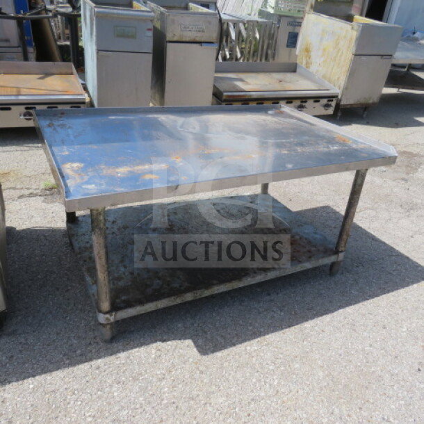 Stainless steel equipment table with under shelf, showing signs of wear and rust, sturdy construction, ideal for industrial use.