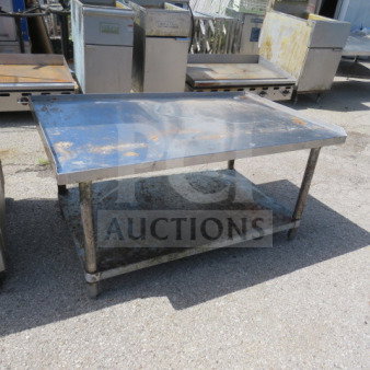Stainless steel equipment table with under shelf, showing signs of wear and rust, sturdy construction, ideal for industrial use.