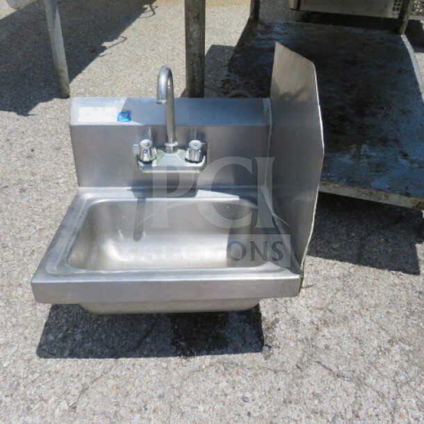 Stainless steel hand sink with faucet, backsplash, and right side splash, 17x15 inches, shown outdoors, good condition.