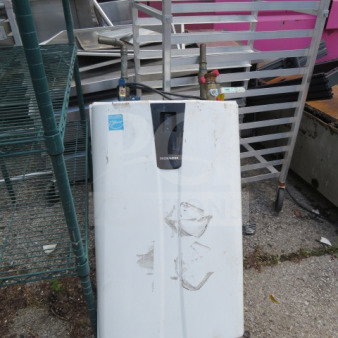 Navien NPE-240A tankless water heater, white, used condition, visible wear, model label on the front.