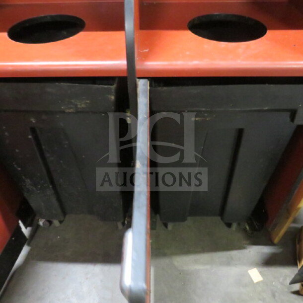 Dual trash receptacle on casters, red with black cans, 42.5x20x45.5 inches, visible wear, suited for sorting waste.