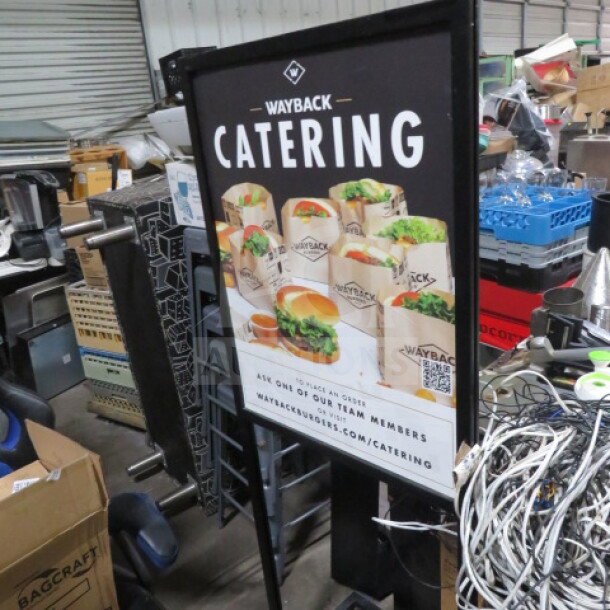 Black metal sign frame, 22.5x25x61 inches, featuring Wayback Catering promotional poster. Used condition, visible in cluttered room.