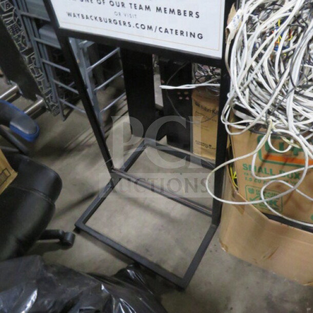 Black metal sign frame, 22.5x25x61 inches, in used condition. Features sturdy construction; ideal for signage display.