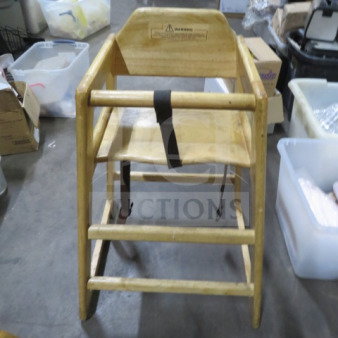 Wooden high chair with safety straps, natural finish, visible wear, and warning label on the backrest.