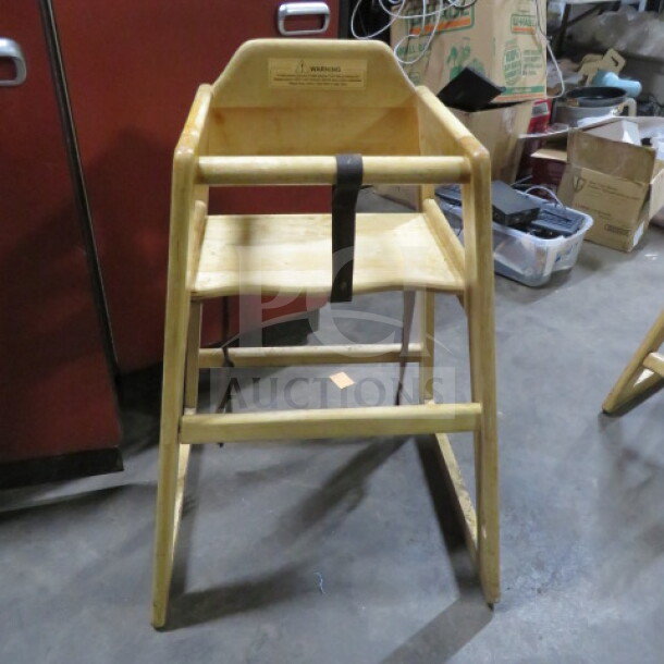 Wooden high chair with safety straps, natural finish, sturdy build, visible warning label, used condition.