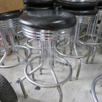 Chrome bar stool with a black cushioned swivel seat, featuring a polished chrome ring. Good condition. Model: 2XBID.