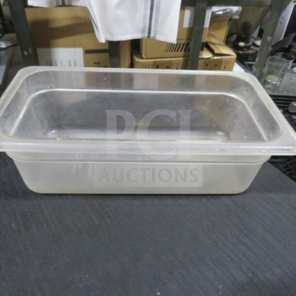 1/3 size food storage container, 4 inches deep, clear material. Shows signs of use, ideal for kitchen or restaurant storage.