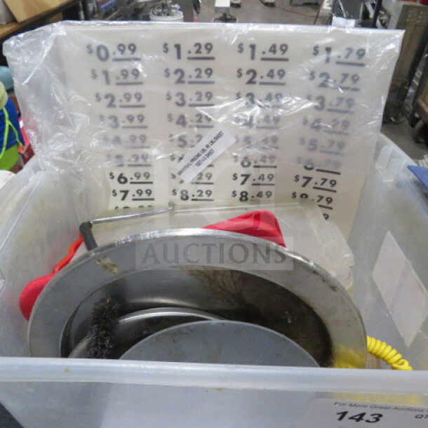 Lot of miscellaneous kitchen items including stainless cookware, red cloth, price signage, and coiled yellow cord.
