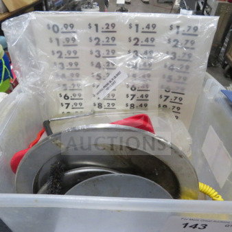 Lot of miscellaneous kitchen items including stainless cookware, red cloth, price signage, and coiled yellow cord.