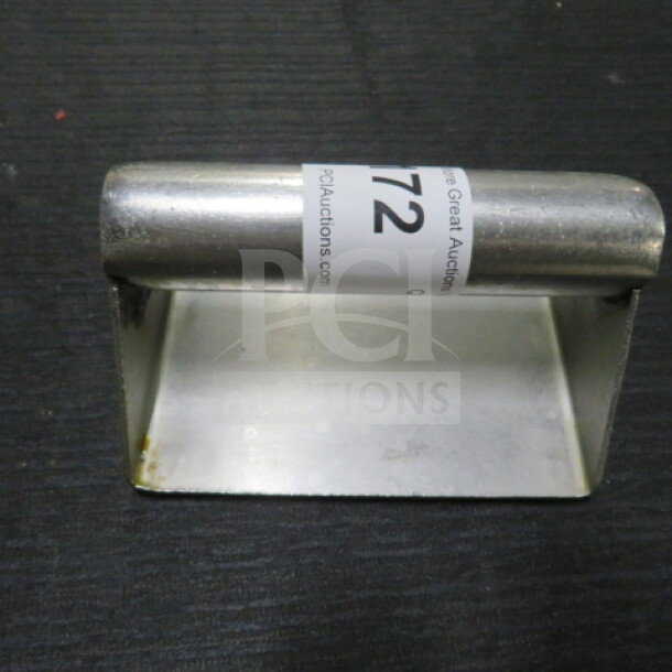 Stainless steel steak weight with handle, used condition, auction tag visible.