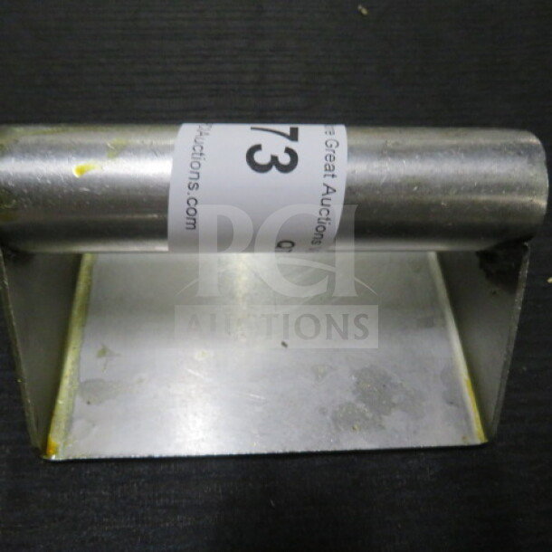 Stainless steel steak weight, rectangular base with handle, minor surface wear, auction label visible.