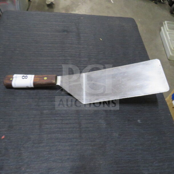 XXL hamburger turner with stainless steel blade, wooden handle, and numbered tag. Good condition.