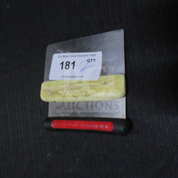 Stainless steel dough cutter with dual handles, one yellow and one black with a red grip. Auction tag "181" visible. Used condition.