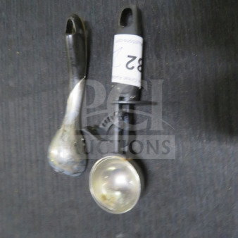 Assorted utensils, including a metal ice cream scoop and a spoon, both in used condition. Item labeled "82".