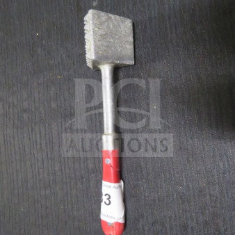 Metal meat tenderizer with a textured head and a red handle, showing wear. Auction tag attached to handle.