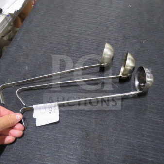 Three 2oz stainless steel ladles with long handles, shown on a dark surface. Each is in good condition, with one displaying a tag labeled "3XBID."