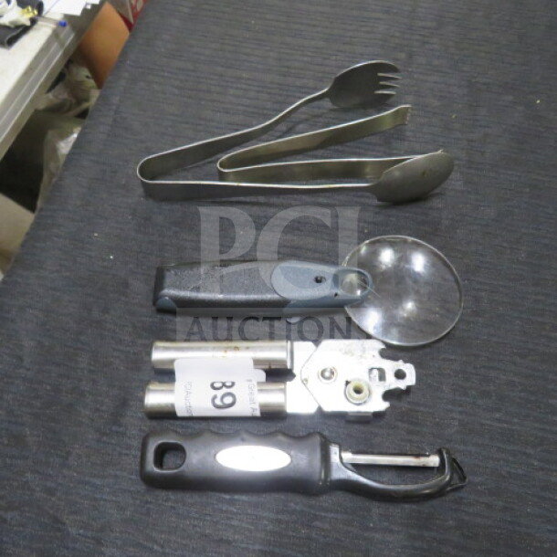 Assorted kitchen utensils including tongs, can opener, pizza cutter, and peeler on black surface, labeled "89".