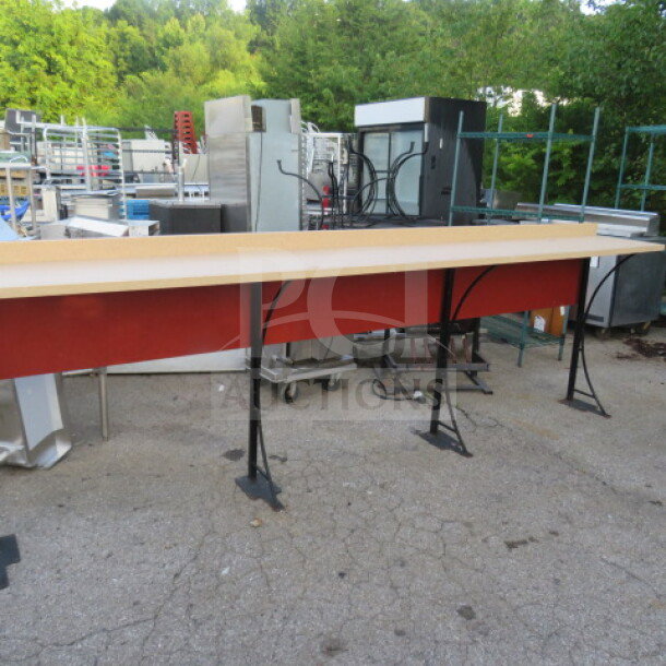 Stand-alone laminate bar with four metal bases, measuring 138x19x45 inches. Good condition, red paneling, sturdy construction.