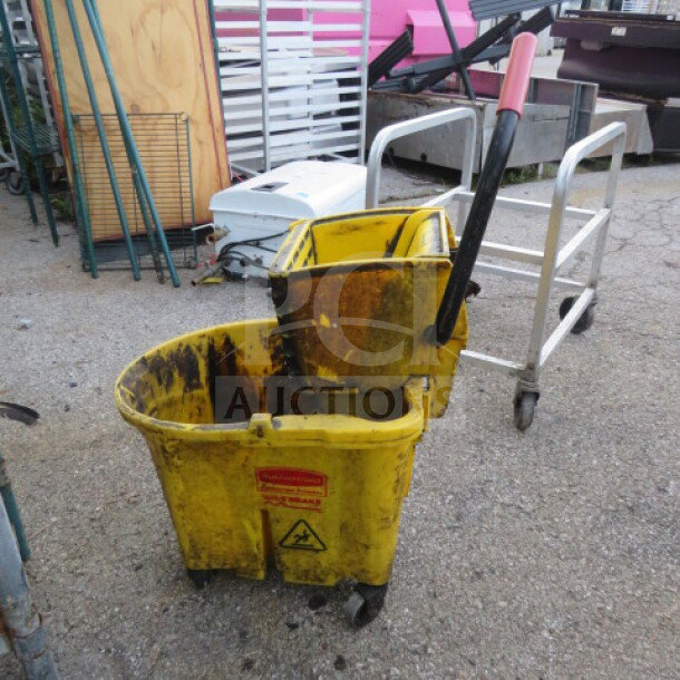 Rubbermaid mop bucket with wringer, yellow, used condition, visible wear, attached handle, caution label on front.