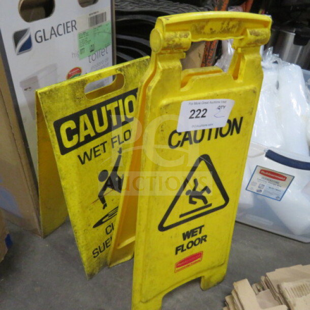 Assorted yellow caution wet floor signs, two pieces, featuring bold text and slipping figure icon, fair condition.