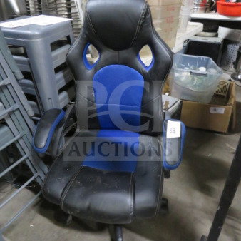 Black and blue gaming chair on casters, with ergonomic design and padded armrests. Some visible wear on seat and back.
