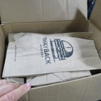 Box of Wayback Burgers paper bags, featuring the logo and website. Bags appear new and neatly stacked.