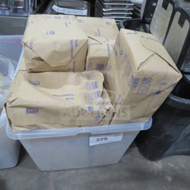 Bulk lot of Tork napkins in original packaging, stacked in a plastic container. Appears unused and in good condition.