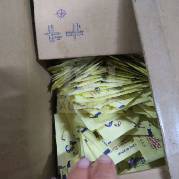 Opened case of Splenda packets, partially filled. Yellow packets visible, marked with "Made in the USA." Box shows handling marks.