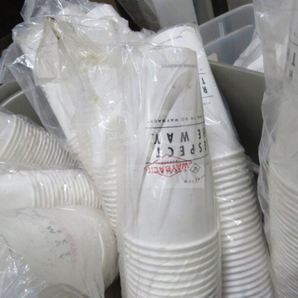 Lot of white paper cups in plastic packaging. Cups labeled "Hygrade" and "Inspected WAX" hinting at durability and quality.