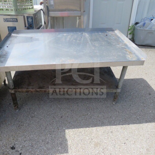 Stainless steel equipment table with undershelf, 48x30x25 inches. Shows signs of wear. Ideal for kitchen or industrial use.