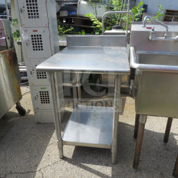 Stainless steel table with under shelf and backsplash, 24x30x39 inches, used condition, ideal for kitchen or industrial use.