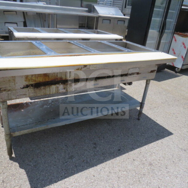 Eagle 4 well steam table with undershelf and cutting board, dimensions 64x30.5x34, used condition, visible wear.