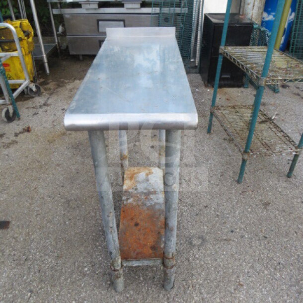 Stainless steel table with under shelf, dimensions 12x30x34.5 inches, showing signs of rust and wear.