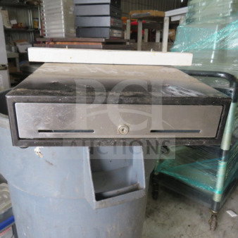 Metal cash drawer with lock, black finish, visible wear, key slot at front. Ideal for retail or office use.