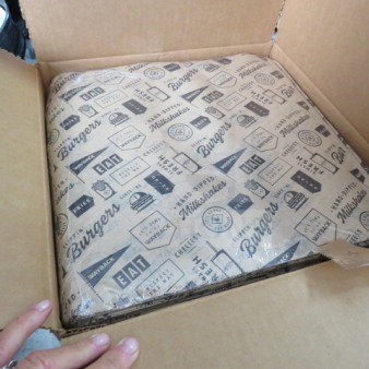 Box of 5,000 13x13 paper liners with food-themed graphics, new condition, ideal for burger and sandwich wrapping.