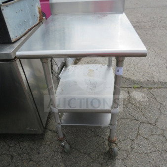 Advance Tabco stainless steel table, model KMS-302, features two under shelves, backsplash, and casters. Size: 24x30x41.5 inches.